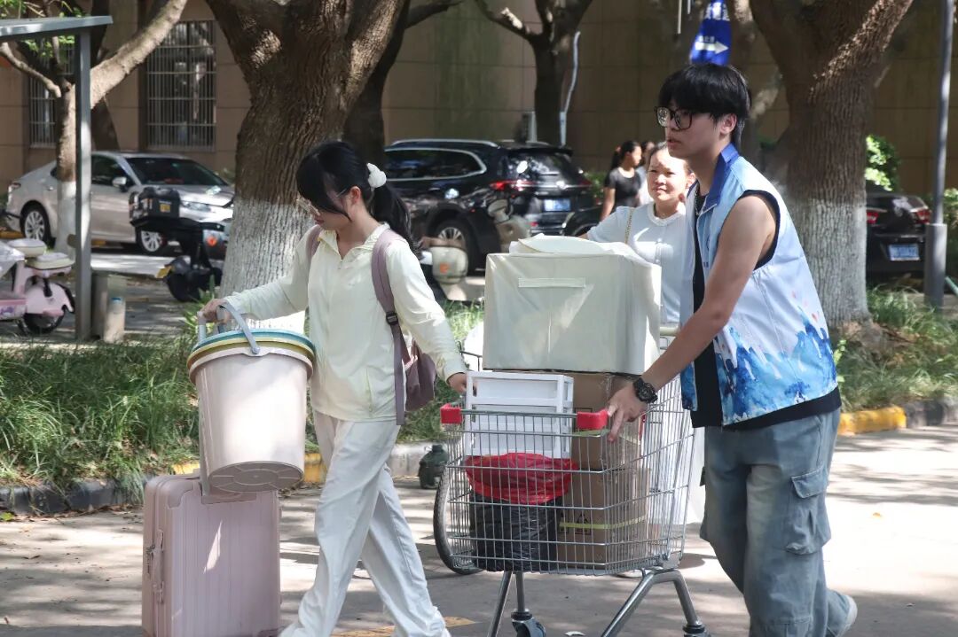 图为：志愿者和同学一起搬行李.JPG